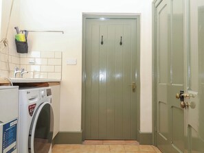 A laundry area with a washing machine, a sink, and a door. - Lukesland Wing (Ivybridge)