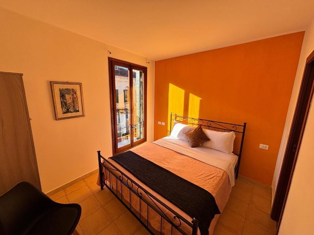 Ein Schlafzimmer mit Bett, Fenster, Tür und Stuhl.