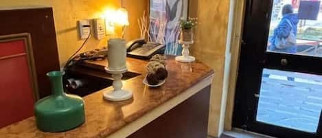 Una recepción con un teléfono, un objeto verde y un cuadro en la pared.