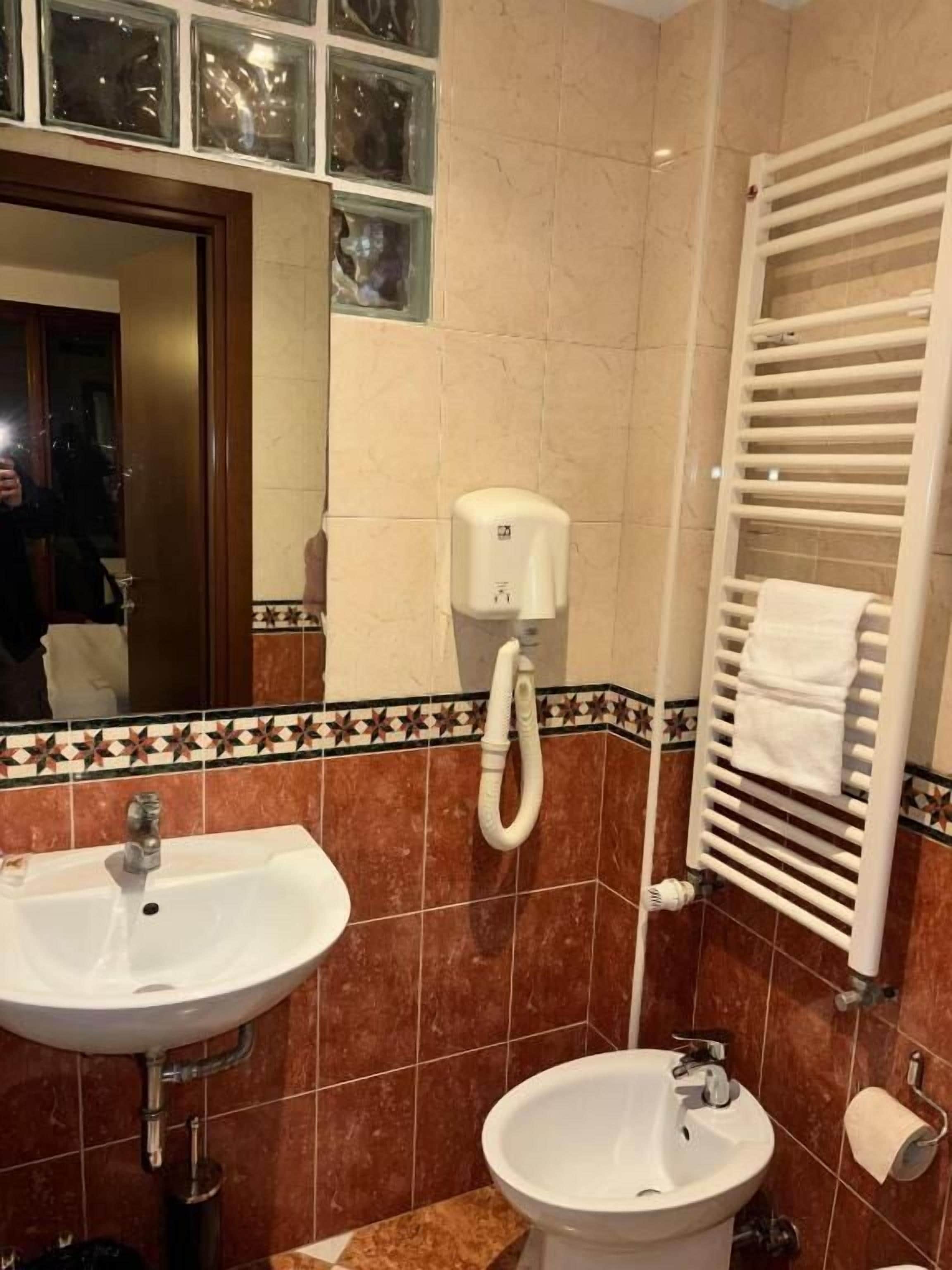 Une salle de bain équipée d’un lavabo, de toilettes et d’un porte-serviettes.