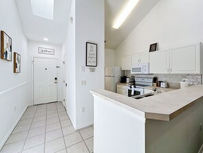Een moderne keuken met witte kastjes, een inbouwoven, magnetron en spoelbak.