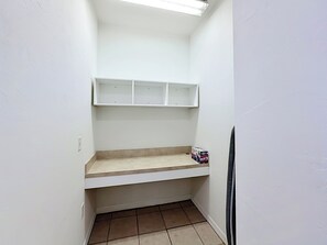 Een kleine, smalle kamer met een witte muur, een plankenwand en een betegelde vloer.