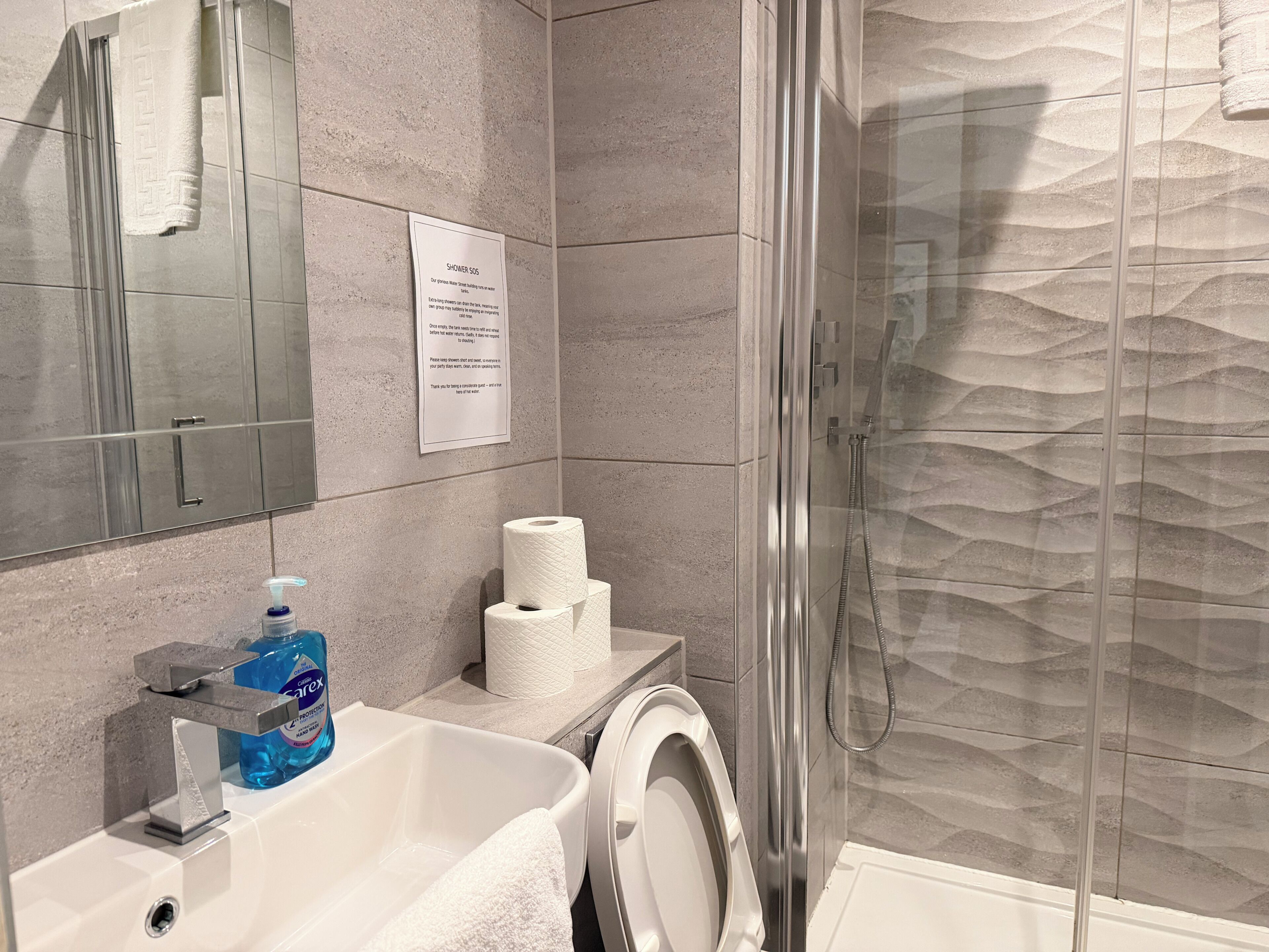 Une salle de bain équipée d’une douche, de toilettes, d’un lavabo et d’une cabine de douche en verre.