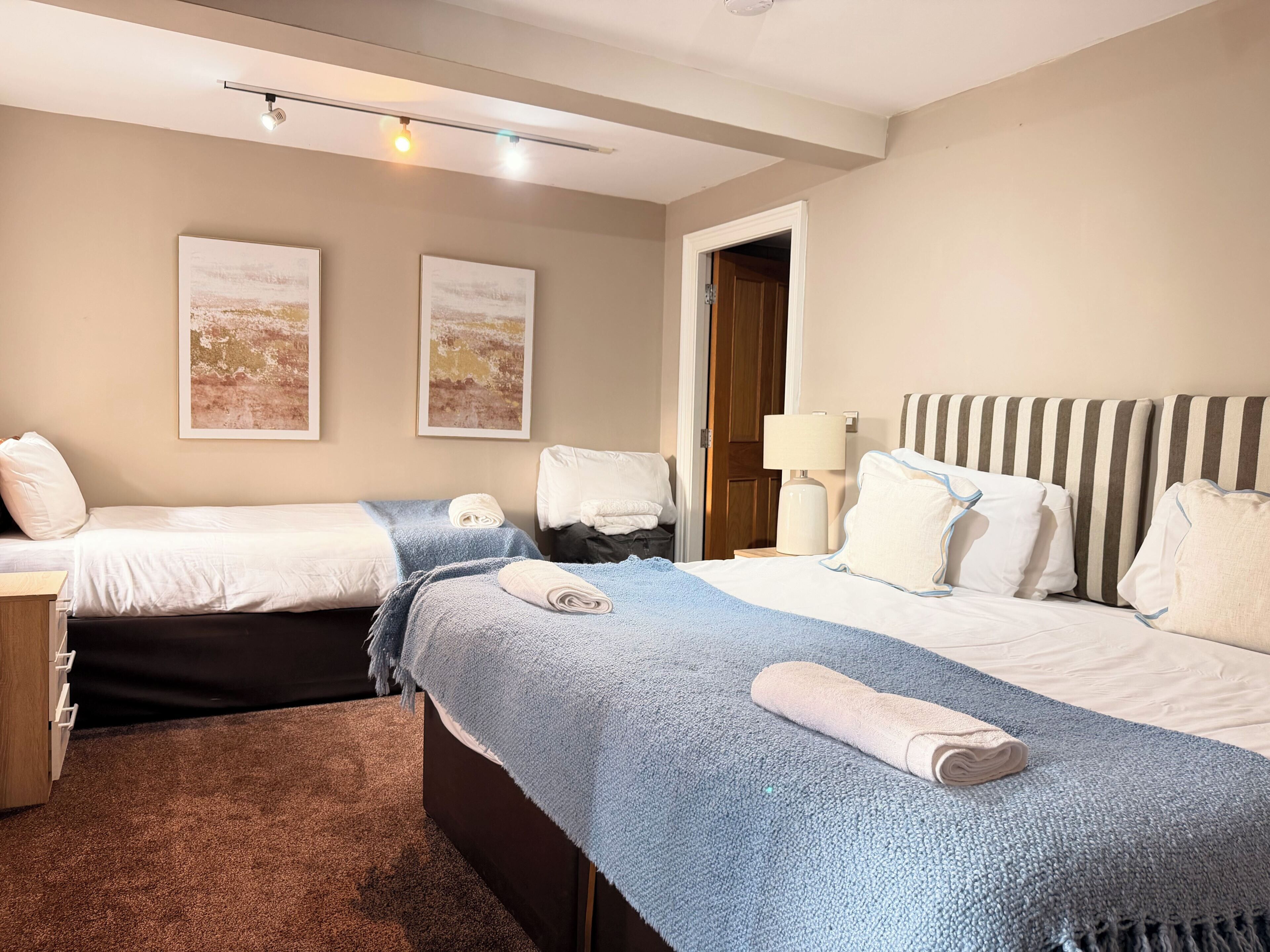 Ein Hotelzimmer mit zwei Betten, einem Nachttisch, einer Lampe und Bildern an den Wänden.
