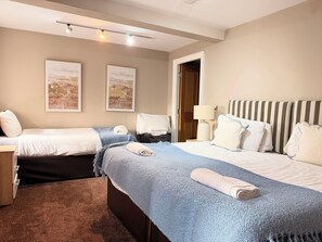 A hotel room with two beds, a nightstand, a lamp, and artwork on the walls. - Swiss Apartments (Liverpool)