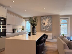 Una cucina moderna con un'isola centrale, elettrodomestici in acciaio inossidabile e un grande quadro decorativo.
