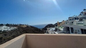A coastal view with buildings, a clear sky, and the sun. - Amadores Paradise – Entire House (2 Connected Apartments) with the Complex's Pool (Mogán)