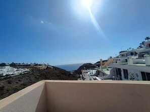 A coastal view with buildings, a clear sky, and the sun. - Amadores Paradise – Entire House (2 Connected Apartments) with the Complex's Pool (Mogán)