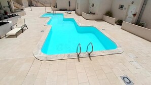 A swimming pool with two diving boards, a covered seating area, and a staircase leading to upper levels. - Amadores Paradise – Entire House (2 Connected Apartments) with the Complex's Pool (Mogán)