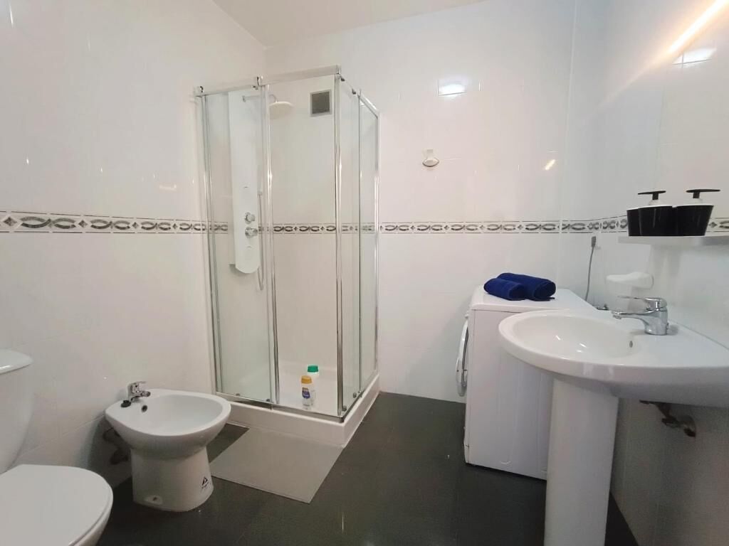 A bathroom with a toilet, bidet, shower, and sink.
