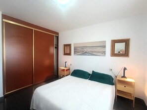 A bedroom with a bed, a nightstand, a lamp, a wardrobe, and a framed picture on the wall. - Amadores Paradise – Entire House (2 Connected Apartments) with the Complex's Pool (Mogán)