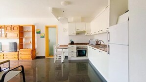 A modern kitchen with white cabinets, a built-in oven, and a dining area with a table and chairs. - Amadores Paradise – Entire House (2 Connected Apartments) with the Complex's Pool (Mogán)