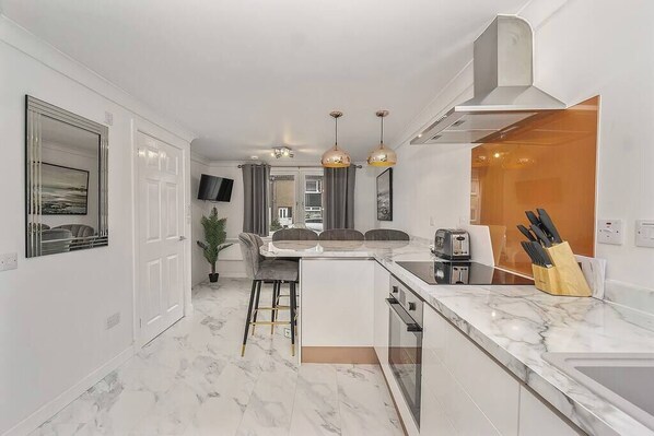 A modern kitchen with a marble countertop, a central island, and pendant lighting.