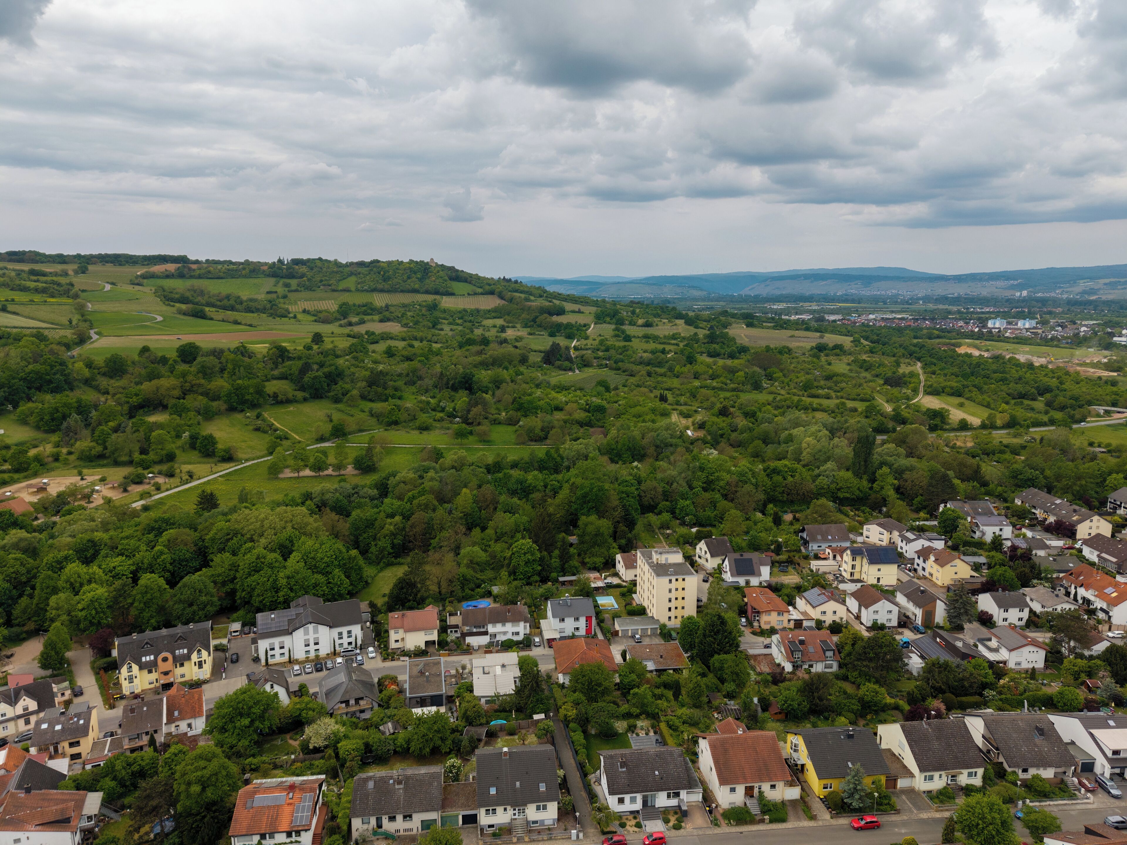 A residential area with houses, roads, and green fields.