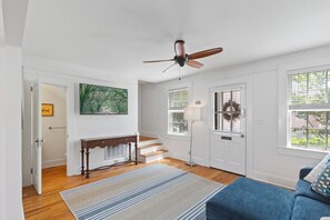 A room with a ceiling fan, a staircase, a door with a wreath, and a large window. - Historic Charleston Rowhome in heart of downtown, walkable, private and charming (Charleston)