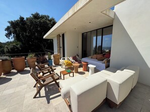 A modern outdoor seating area with a sofa, chairs, and potted plants. - Architect-designed villa with a pool and a view of the Mediterranean – Sleeps 9 (Rayol-Canadel-sur-Mer)