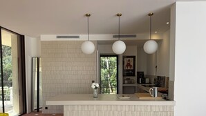 A modern kitchen with a central island, pendant lighting, and a view of greenery outside. - Architect-designed villa with a pool and a view of the Mediterranean – Sleeps 9 (Rayol-Canadel-sur-Mer)
