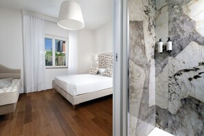 A bedroom with a bed, a sofa, a window with curtains, and a marble wall with two bottles. - Luxury Authentic Italian Villa with Private Pool & Iconic Seaview Terrace (Massa Lubrense)