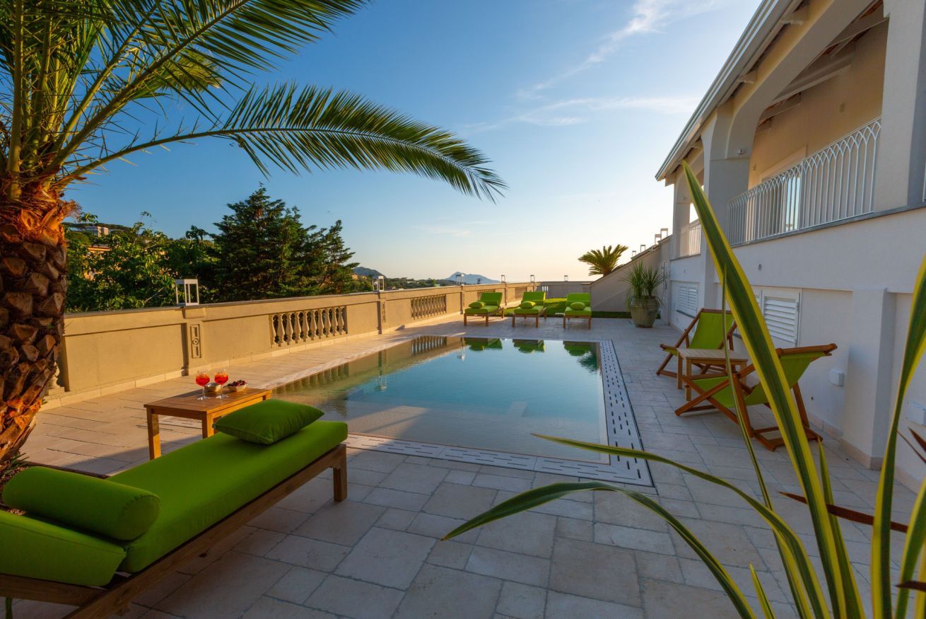 Zona de piscina al terrat amb gandules i una palmera.