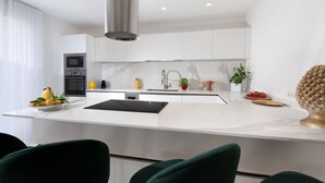 A modern kitchen with white cabinetry, a central island, and a stainless steel range hood. - Luxury Authentic Italian Villa with Private Pool & Iconic Seaview Terrace (Massa Lubrense)