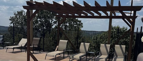 A poolside area with a pergola, lounge chairs, and a swimming pool.