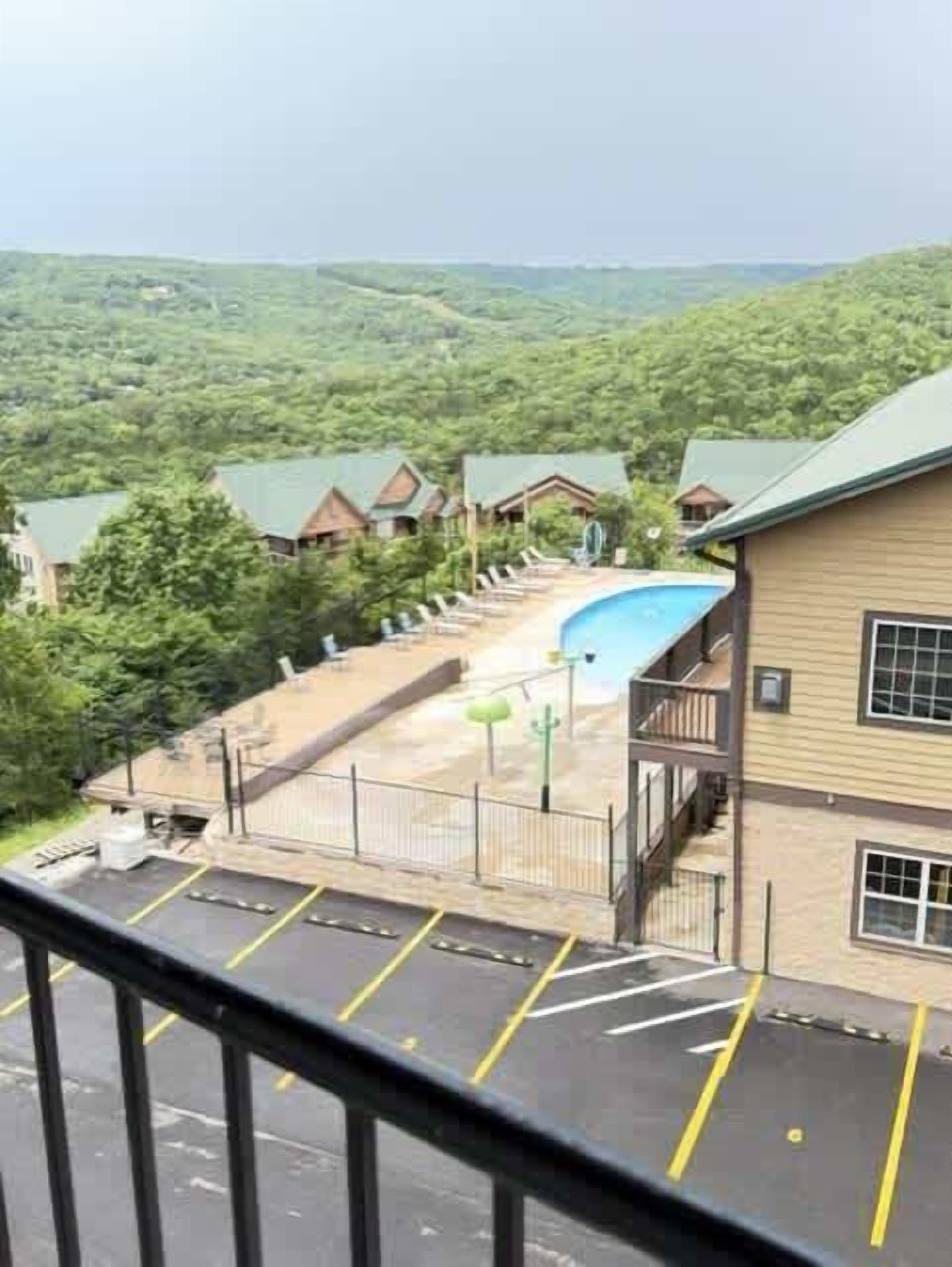 Ein Hotel mit Pool, Parkplatz und Blick auf die umliegende Grünfläche.