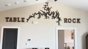 Ein Zimmer mit Deckenventilator, einem Bett, einem Couchtisch und einer Wand, auf der oberhalb einer Zierpflanze der Schriftzug 'TABLE ROCK' steht.