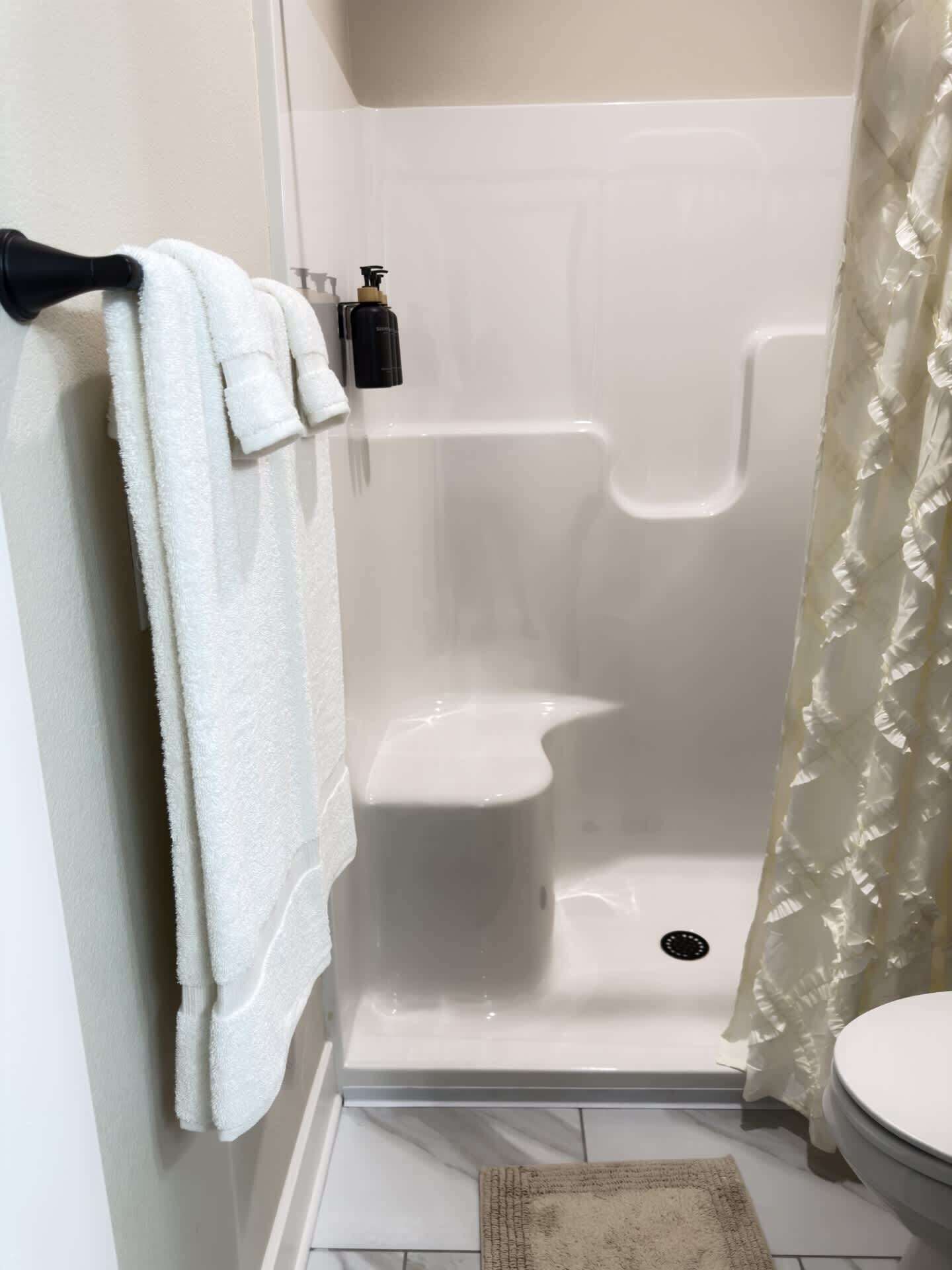 A bathroom with a shower, toilet, and towel rack.