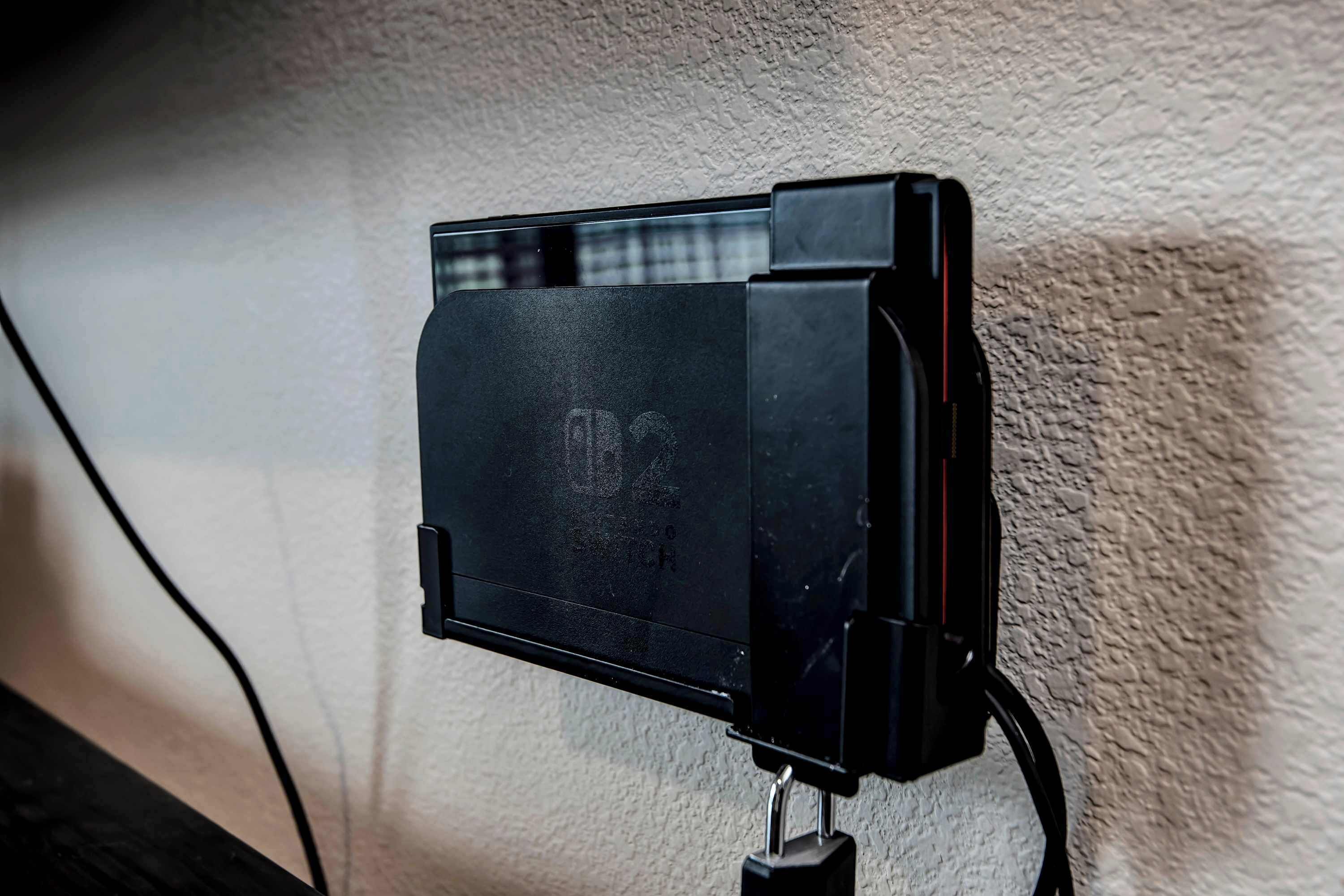 Ein schwarzes elektronisches Gerät an einer strukturierten Wand montiert, verbunden durch ein Kabel.