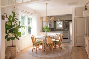 A dining area with a round table, four chairs, a potted plant, and a hanging light fixture. - 3-bedroom professionally designed bungalow in tranquil Vero Beach, Fl. (Vero Beach)