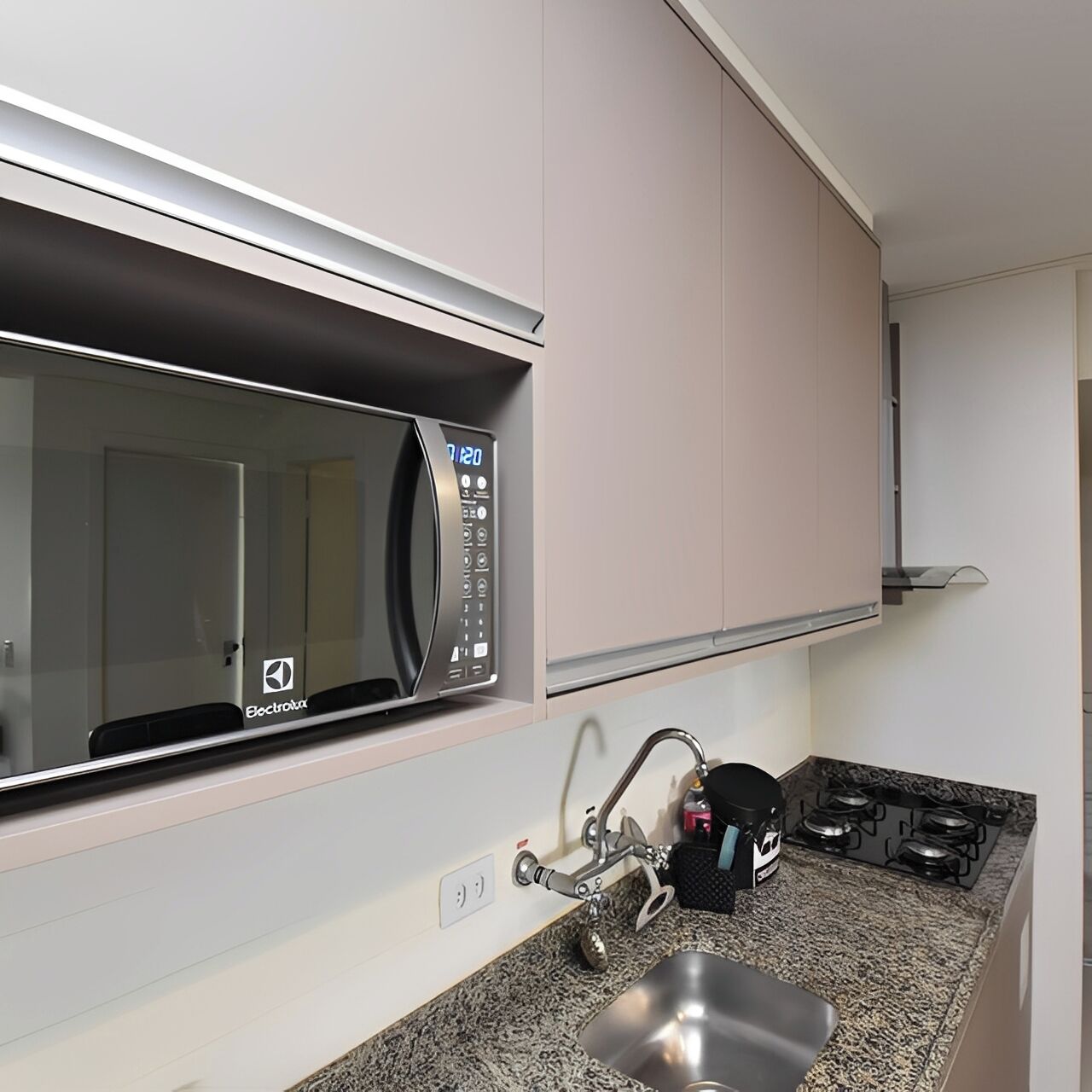 Uma cozinha equipada com micro-ondas, pia, torneira e fogão.