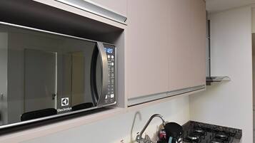 Uma cozinha equipada com micro-ondas, pia, torneira e fogão.