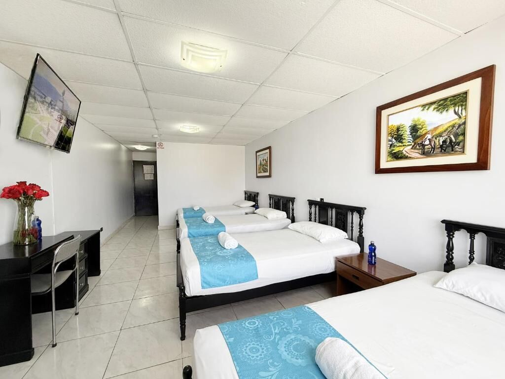 Ein Hotelzimmer mit drei Betten, einem Schreibtisch und einem Stuhl.