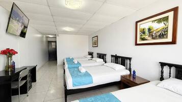 Habitación de hotel con tres camas, un escritorio y una silla.