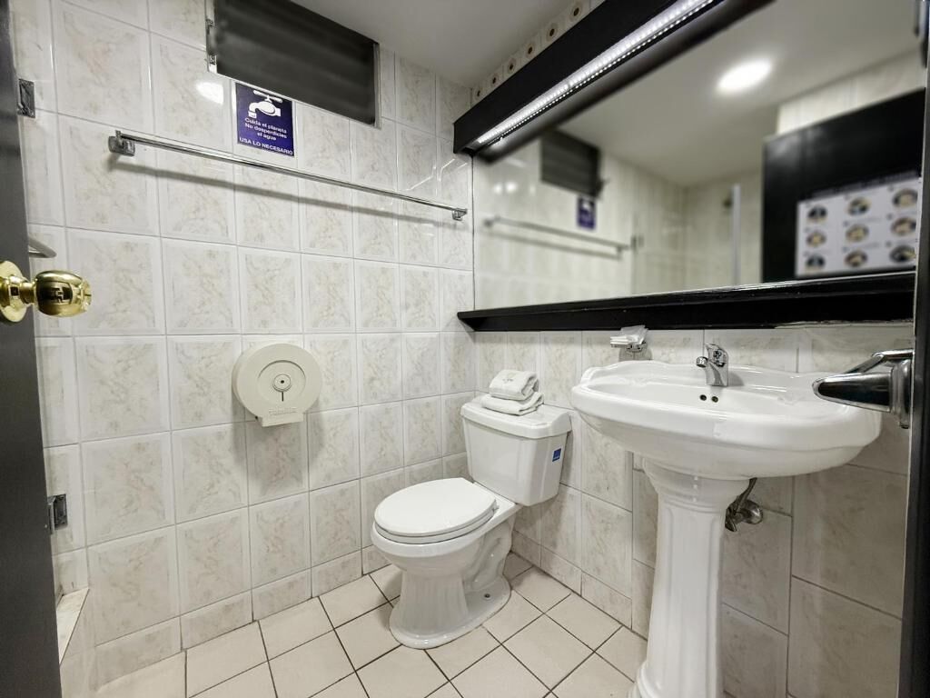 Un baño pequeño y moderno con inodoro, lavamanos y secamanos.