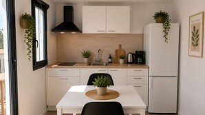 Una cucina moderna con un piano di lavoro bianco, una sedia nera e un frigorifero bianco.