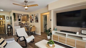 A living room with a sofa, a TV, a ceiling fan, and a dining area with chairs and a table. - La Felicidad Apartment, Dénia, Next to the Beach (Dénia)