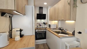 A compact kitchen with a microwave, oven, sink, and wooden countertop. - La Felicidad Apartment, Dénia, Next to the Beach (Dénia)