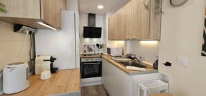 Eine kleine Küche mit Mikrowelle, Backofen, Spüle und Arbeitsplatte aus Holz.