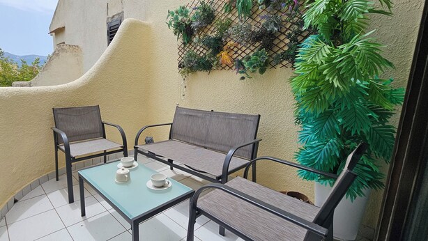 A balcony with two chairs and a table, a potted plant, and a view of buildings and mountains. - La Felicidad Apartment, Dénia, Next to the Beach (Dénia)
