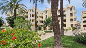 A multi-story residential building with balconies, surrounded by palm trees and greenery. - La Felicidad Apartment, Dénia, Next to the Beach (Dénia)