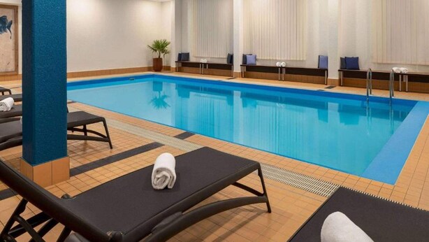 Ein Schwimmbecken mit Liegestühlen, einer Topfpflanze und einer blauen Säule.