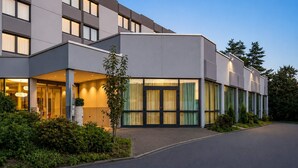 Ein modernes Hotel mit flachem Dach, großen Fenstern und einem gepflegten Garten.