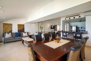 A spacious living area with a dining table, sofas, and a kitchen in the background. - Private Villa 3 in Cancún - Villas del Mar (Cancún)