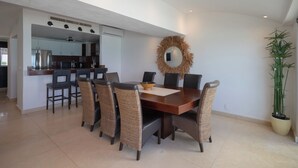 Un comedor con mesa de madera, sillas de mimbre, un espejo y una planta en maceta.