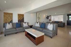 A spacious living room with a sectional sofa, a coffee table, and artwork on the walls. - Private Villa 3 in Cancún - Villas del Mar (Cancún)