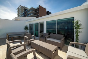 An outdoor patio with wicker furniture, a dining table, and a large sliding glass door leading to a covered area. - Private Villa 3 in Cancún - Villas del Mar (Cancún)