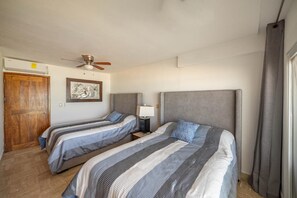 A hotel room with two beds, a ceiling fan, a painting on the wall, and a wooden door. - Private Villa 3 in Cancún - Villas del Mar (Cancún)