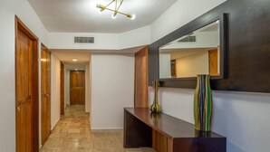 Un pasillo con puertas de madera, un banco, un espejo y un florero.