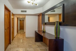 A hallway with wooden doors, a bench, a mirror, and a vase.